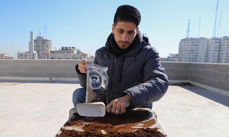 2023 年 1 月 19 日、アブドゥラ アル サファディはコーヒーかすを集めて、ガザ市の植物の肥料として使用します。彼のコミュニティ。 (写真提供: Rizek Abdeljawad/Xinhua)
