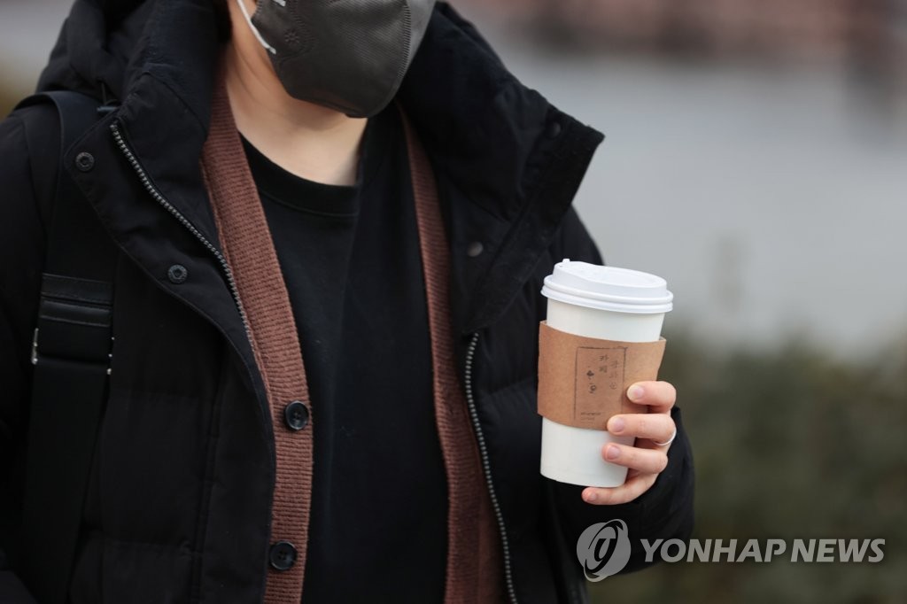2023 年 1 月 16 日に撮影されたこのファイル写真では、歩行者がソウル中心部でコーヒーを飲んでいます。 (聯合)